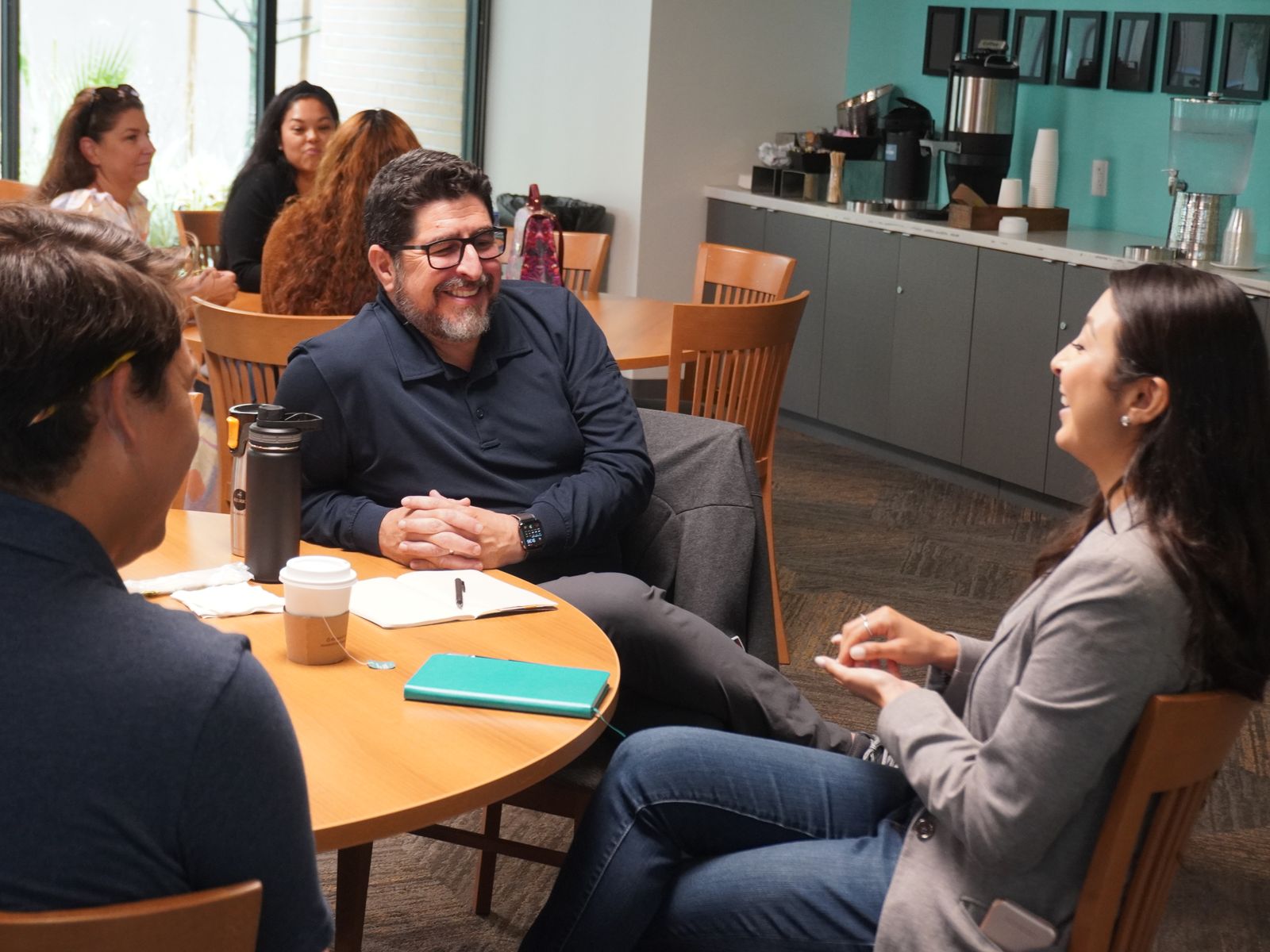 Three workshop participants talking and laughing together around a table