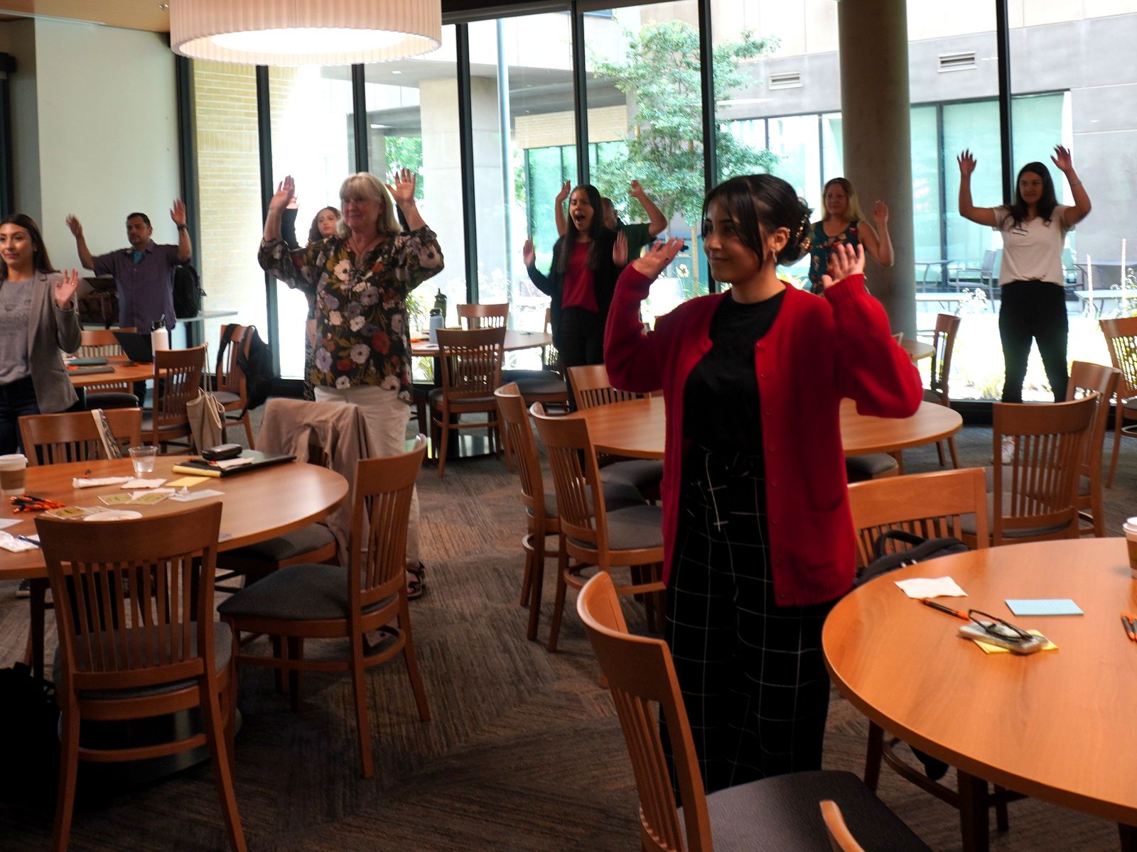Workshop participants standing with their hands raised during an interactive learning activity